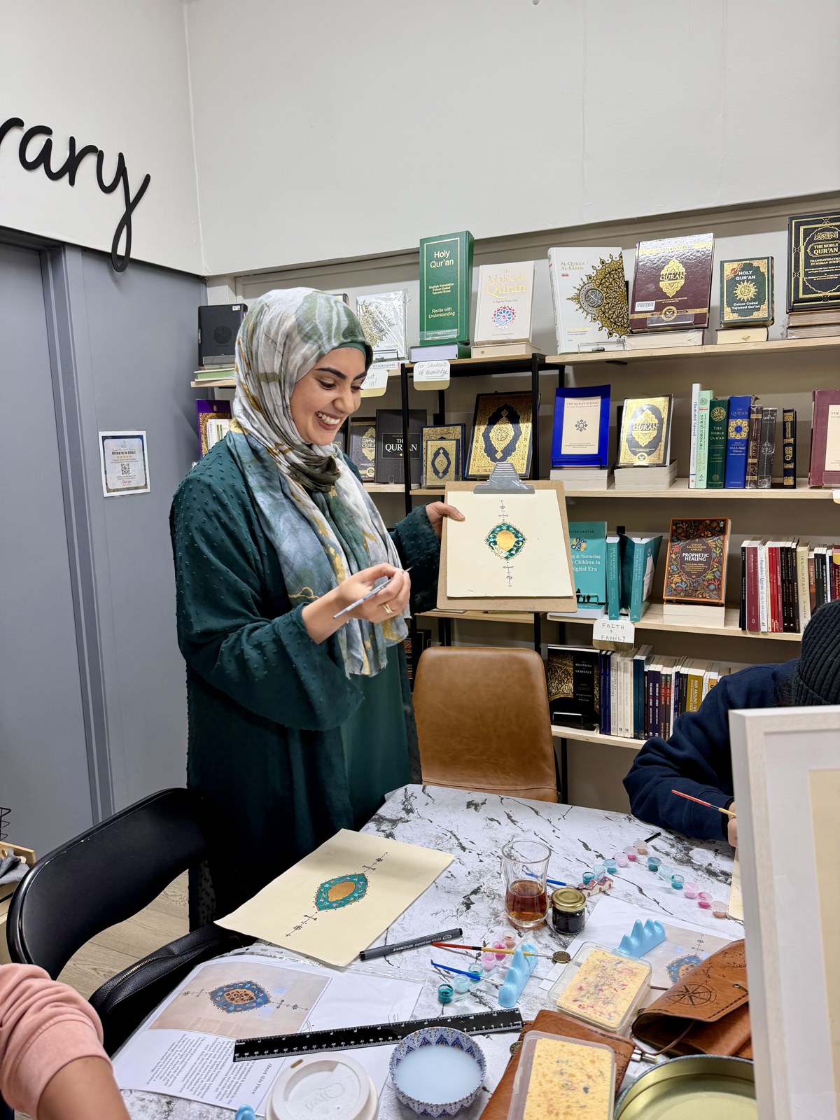 A workshop participant sharing her illuminated artwork at the table