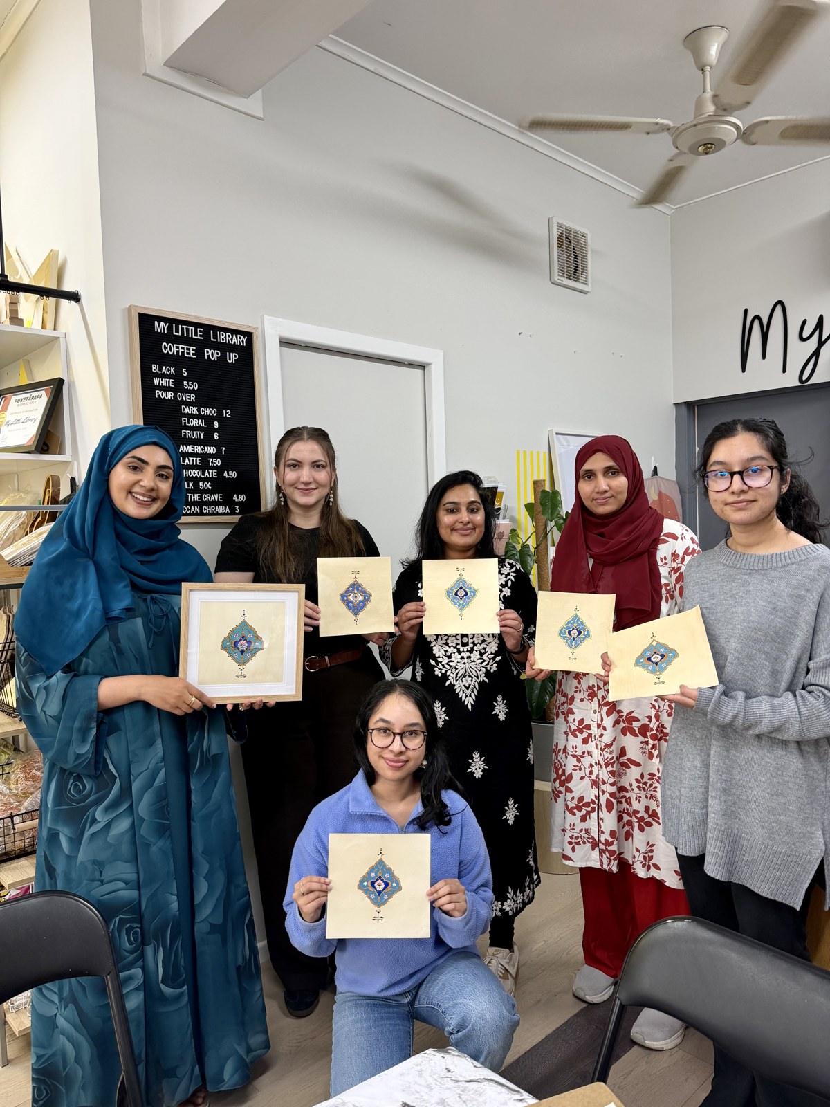 Workshop participants holding their finished illuminated artworks